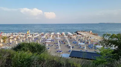 a beach with a lot of chairs and people on it at Balcony Bliss: The Black Sea Pearl in Sveti Vlas