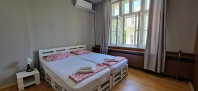 a bedroom with a bed with pink pillows and a window at Lambo's Corner Varna - Guest Rooms in Varna City