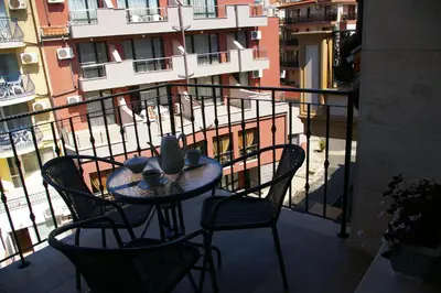 a table and chairs on a balcony with a building at Sea View Apartments in Sozopol