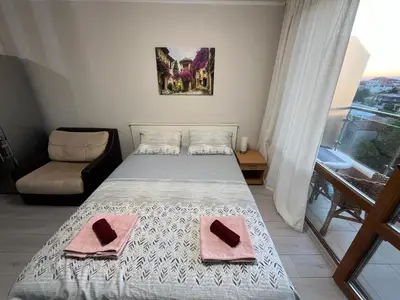 a bedroom with a bed and a chair and a window at Alexandr apartments Vigo Nesebar in Nesebar