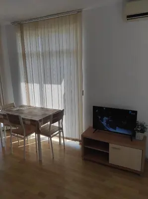 a living room with a table and a tv at Kirovi Apartment in Primorsko