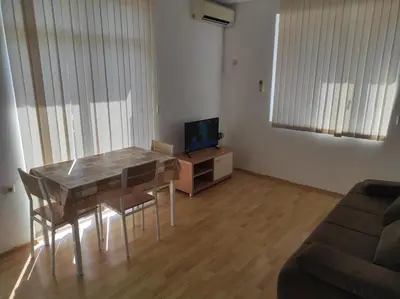 a living room with a dining room table and a television at Kirovi Apartment in Primorsko