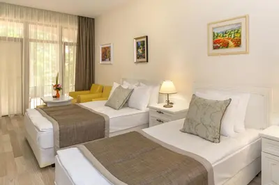 a hotel room with two beds and a yellow chair at Hotel Venus in Sunny Beach