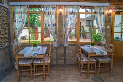 two tables and chairs in a room with windows at Chrystal Guest House in Obzor