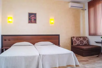 a hotel room with two beds and a chair at Chrystal Guest House in Obzor