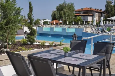 a dining table and chairs next to a swimming pool at Marina Hills in Sozopol