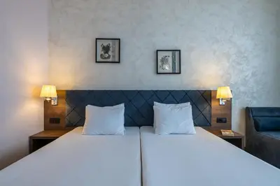 a bedroom with two beds and a blue chair at Flamingo Beach Hotel in Sunny Beach