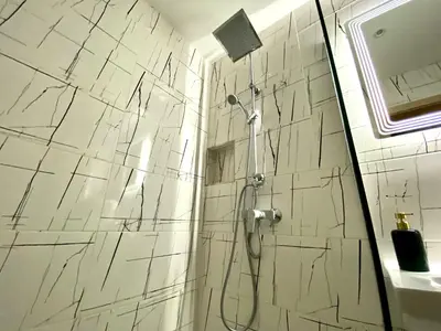 a bathroom with a shower with white marble tiles at AVRORA SUITE in Varna City