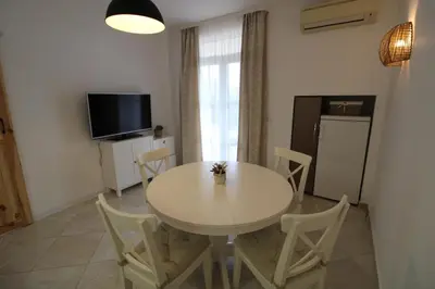 a dining room with a white table and chairs at Flores Garden - Menada Apartments in Chernomorets