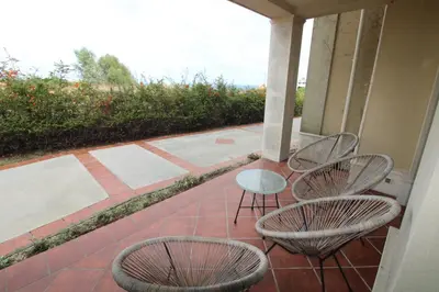 a porch with three chairs and a glass table and chairs at Flores Garden - Menada Apartments in Chernomorets