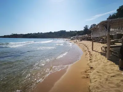 a sandy beach with umbrellas and the ocean at Flores Garden - Menada Apartments in Chernomorets