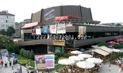 a building with tables and umbrellas in front of it at Festival and Congress Centre Appartment Varna in Varna City