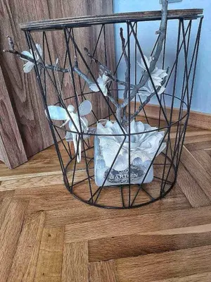 a metal basket with white flowers in it on a wooden floor at Sea Light in Burgas City