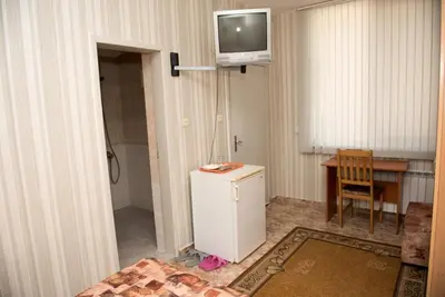 a room with a refrigerator and a table and a television at Стаи за гости in Varna City