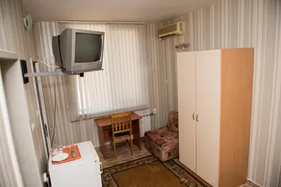 a room with a tv and a chair and a table at Стаи за гости in Varna City