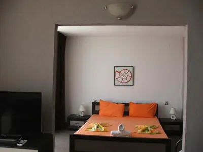 a bedroom with a bed with orange pillows and a tv at Guest House Compass in Lozenets