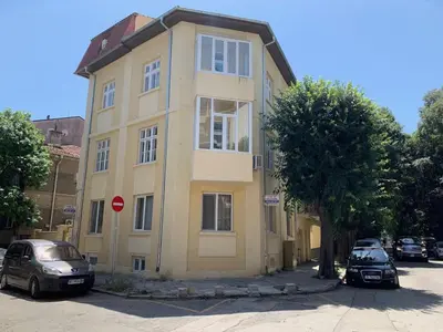 a yellow building with cars parked in front of it at Guest Rooms Donovi in Varna City
