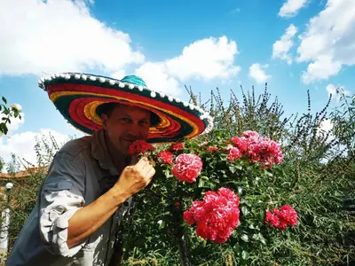 a man wearing a sombrero standing next to flowers at Zapovedni Rai in Primorsko