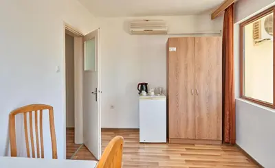 a kitchen with a refrigerator and a table and a door at Hotel Koral in Primorsko