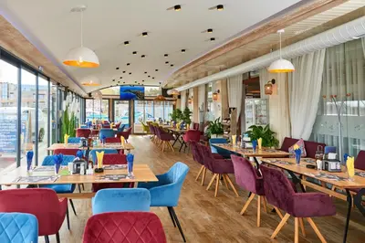 a restaurant with wooden tables and chairs and windows at Petar and Pavel Hotel & Relax Center in Pomorie