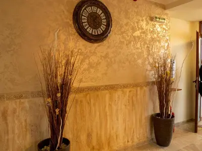 a clock on a wall next to two plants at Petar and Pavel Hotel & Relax Center in Pomorie