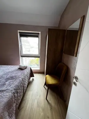 a bedroom with a bed and a chair and a window at Varna downtown apartment in Varna City