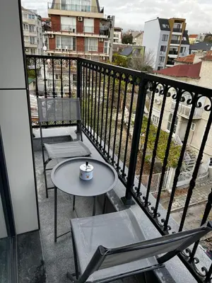 a table and chairs on a balcony with a cup of coffee at Varna downtown apartment in Varna City