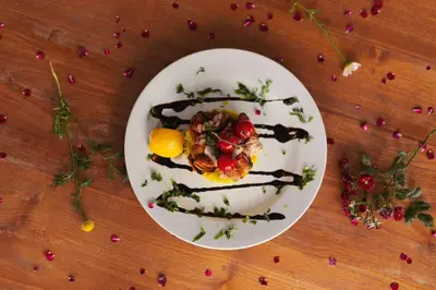 a white plate with food on a wooden table at Villa Livia Boutique Apartments in Ravda