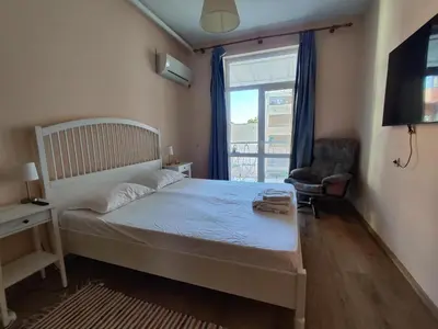 a bedroom with a bed and a chair and a window at Podslon Varna Vibes in Varna City