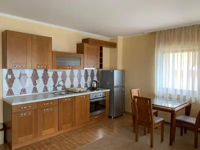 a kitchen with wooden cabinets and a table with chairs at Elizabeth Beach Apartments in Nesebar
