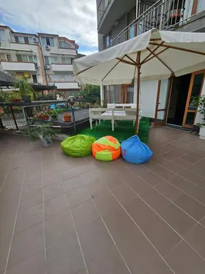 a patio with a table and some bags and an umbrella at Guest House Petrovi in Ravda