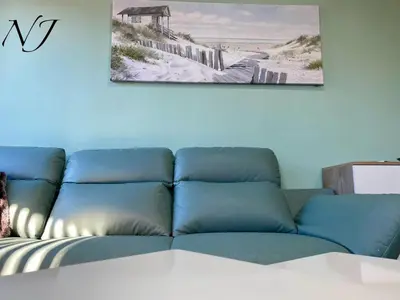 a blue couch in a living room with a picture of a beach at NJ Luxury rooms and suites in Varna City