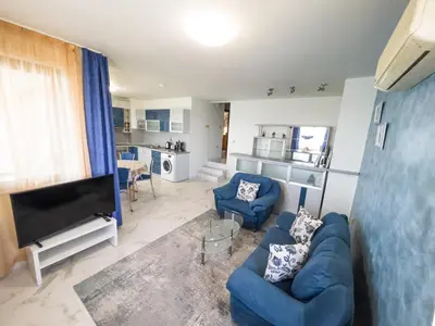 a living room with a blue couch and a tv at Sozopol Apartment with Sea View in Sozopol