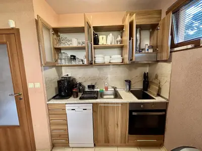 a small kitchen with wooden cabinets and a sink at Guest House Primorsko - Uzundzha in Primorsko