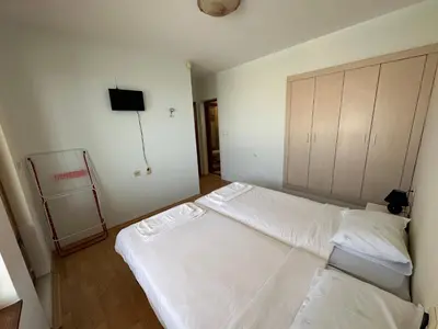 a bedroom with a white bed and a tv at Guest House Primorsko - Uzundzha in Primorsko