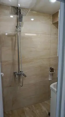 a shower in a bathroom with a wooden wall at Varna Attic Studio - Варна Атик Студио in Varna City