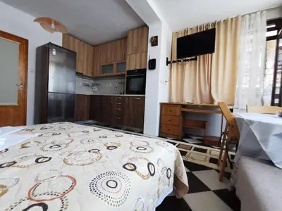 a kitchen with a table and a bed in a room at Guest House Liliya in Sozopol