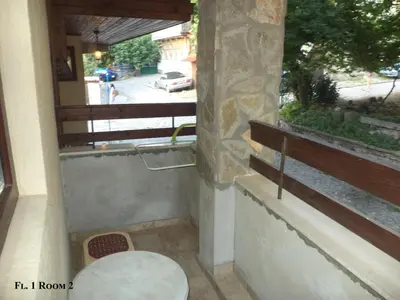 a small balcony with a table and a window at Guest House Liliya in Sozopol