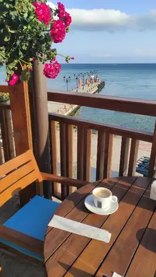 a cup of coffee sitting on a wooden table on the beach at Garden of Eden Sea and Pool View in Sveti Vlas