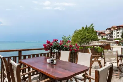 a wooden table and chairs on a balcony overlooking the ocean at Garden of Eden Sea and Pool View in Sveti Vlas