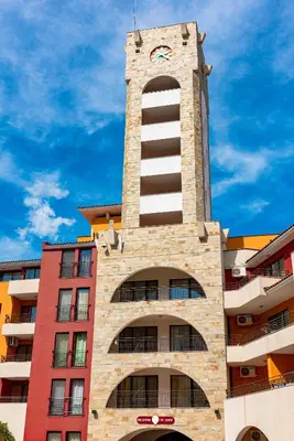 a building with a tower with a clock on it at Menada Aheloy Apartments in Aheloy