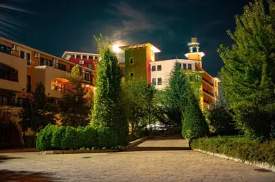 a city street with buildings and trees at night at Menada Aheloy Apartments in Aheloy