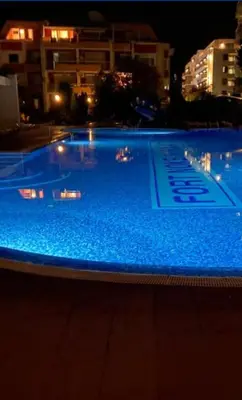 a large swimming pool with blue water at night at Sunny Fort apartments Sanny Beach Parking Free in Sunny Beach