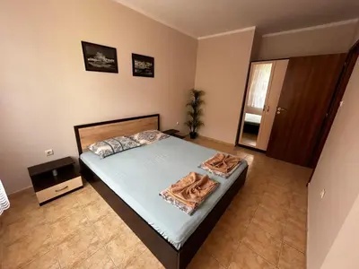 a bedroom with a bed with blue sheets and a plant at Апартамент Александър in Sunny Beach