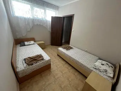 two beds in a small room with a window at Апартамент Александър in Sunny Beach