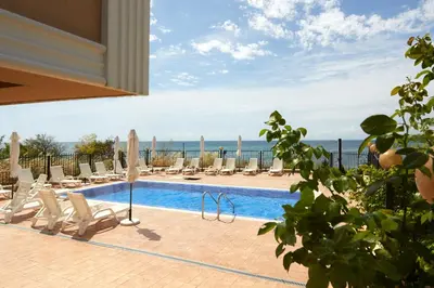 a swimming pool with lounge chairs and the ocean at Mary Beach Resort Premium Apartments in Sveti Vlas