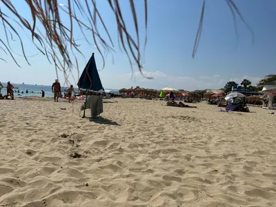 a beach with a blue umbrella and people on it at Complex Compass in Sveti Vlas