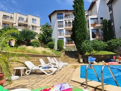 a row of lounge chairs next to a swimming pool at Complex Compass in Sveti Vlas