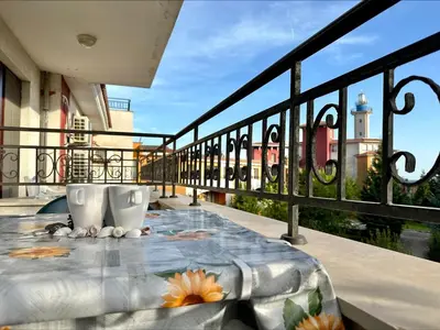 a table on a balcony with a view of a lighthouse at Menada Apartments in Marina Cape in Aheloy