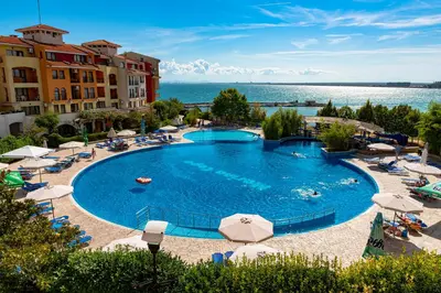a large swimming pool with chairs and umbrellas at Menada Apartments in Marina Cape in Aheloy